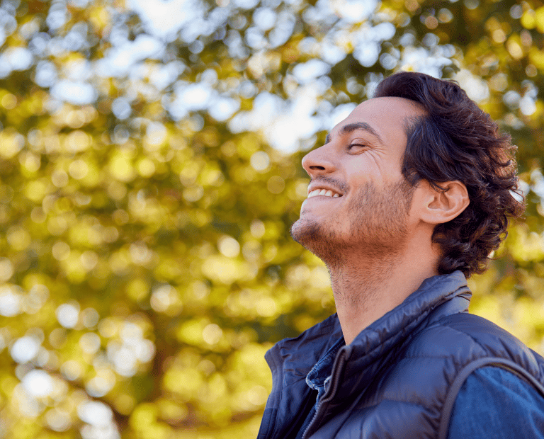 man with eyes closed smiling in nature