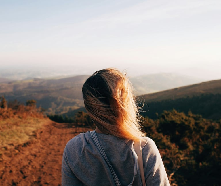 Eine Frau überblickt eine weite Landschaft im Morgenlicht