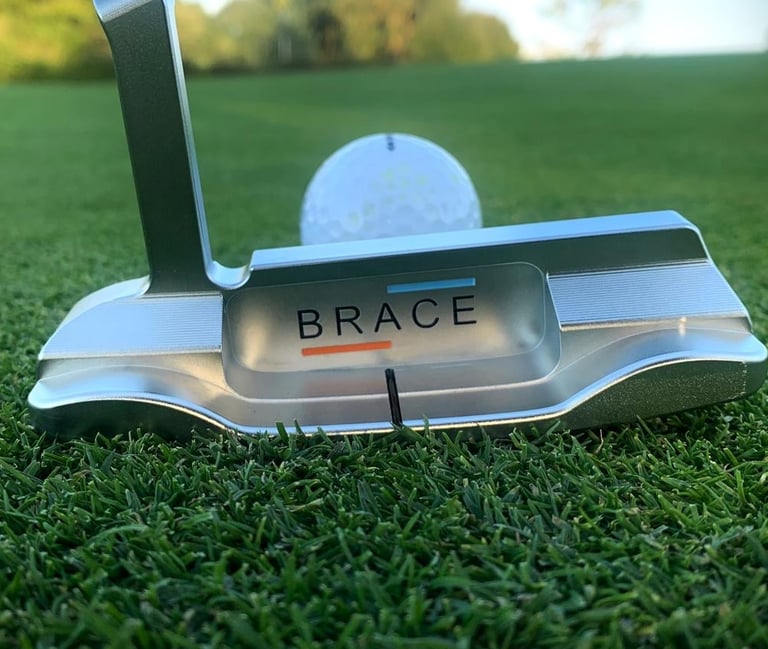 Brace forged golf putter on grass with golf ball