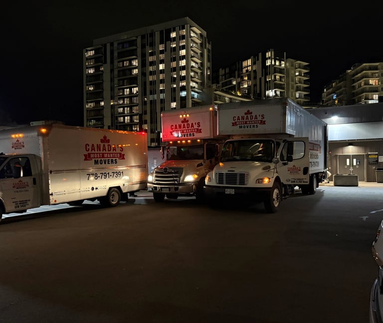 Canada’s Most Wanted Movers fleet parked at night in downtown Vancouver near residential high-rises.