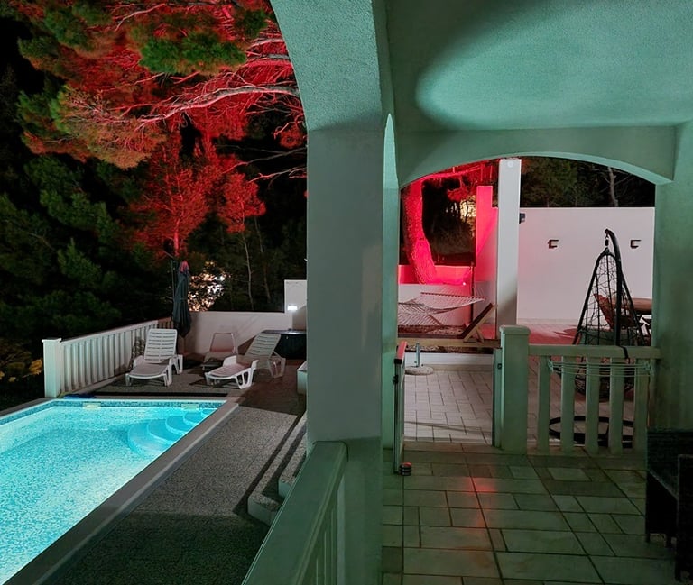 The photograph shows a part of the ground-floor balcony, pool and a courtyard with ambient lighting.