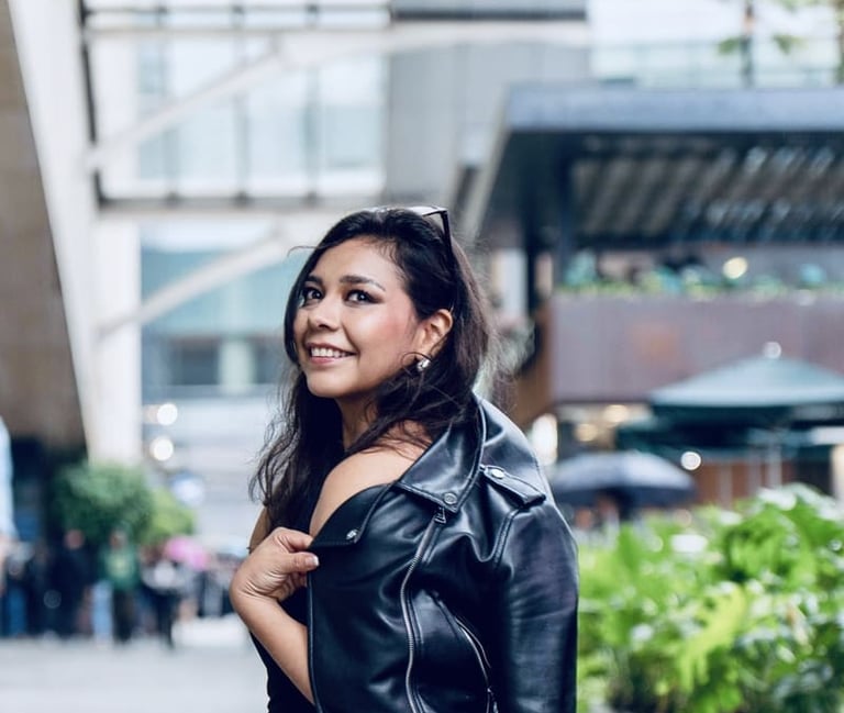 Mujer morena sonriente con chamarra de piel negra.