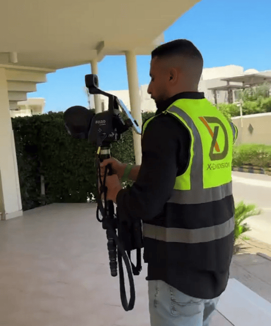 Engineer in a high-visibility safety vest operates a FARO 3D laser scanner on a tripod for hotel.