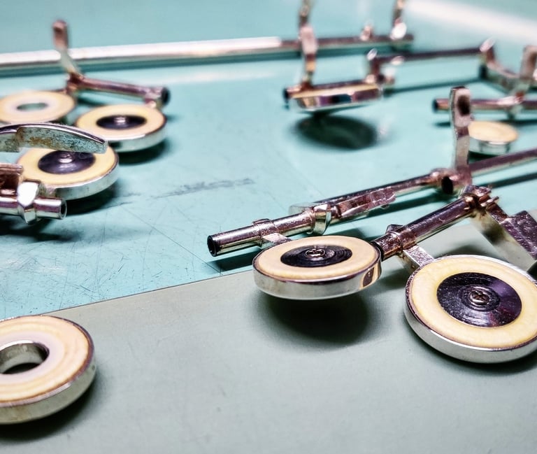 des clefs de flûte traversière posées sur un établi exposant la qualité des tampons de flûte