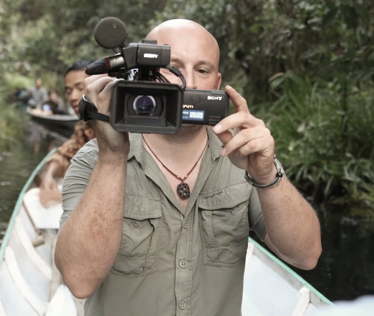 Filmmaker Kevin Augello filming with a Sony camera on a river in the jungle