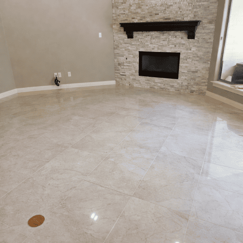 Polished marble tile flooring in a living room featuring a stone fireplace mantel.