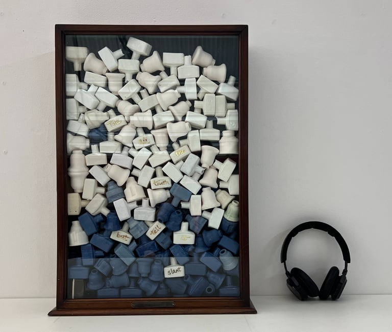A vintage glazed cabinet holds a stack of 100 small ceramic bottles in blue and white porcelain.