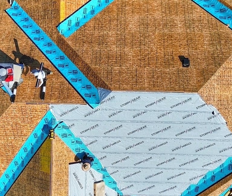 Roofing crew performs maintenance on residential roof replacement by laying Ice & Water protection