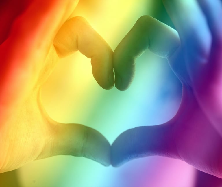 holding hands in a heart shape with a pride rainbow background