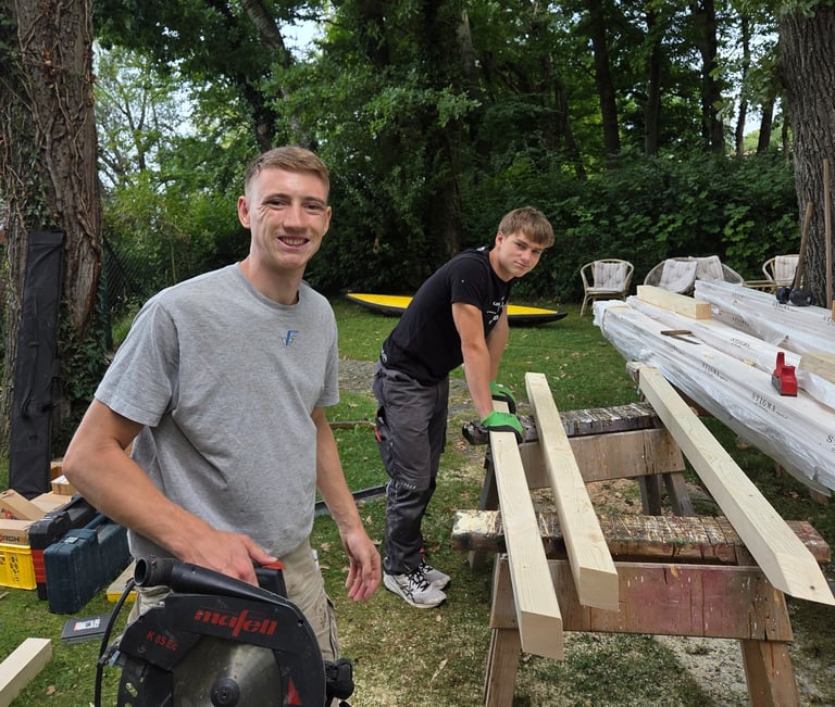 Gut gelaunte Azubis von Holztechnik Volk bei Holzarbeiten im Garten am Ammersee.