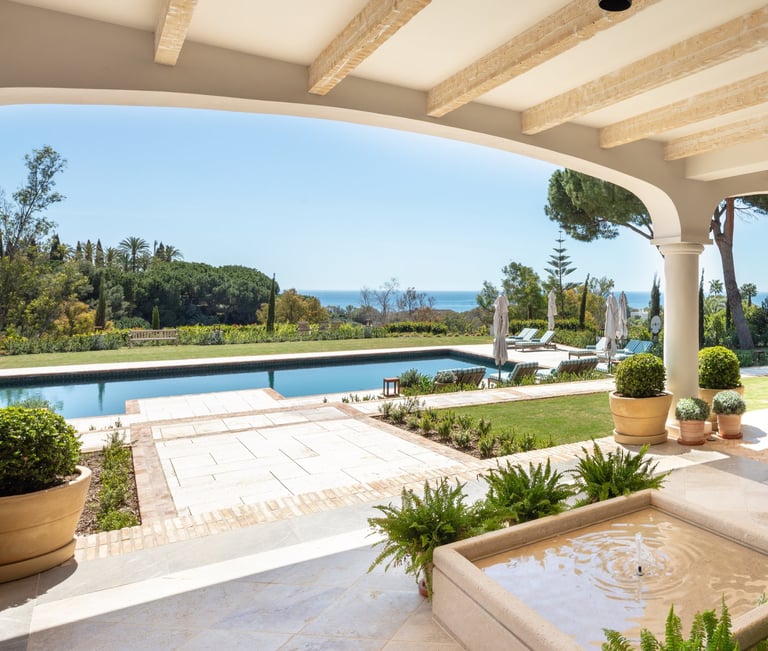 View from the shaded porch across the pool, with the Mediterranean Sea visible in the background.