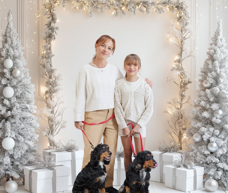 Mother and daughter posing with two spaniel dogs in a white winter holiday studio setting with lights.