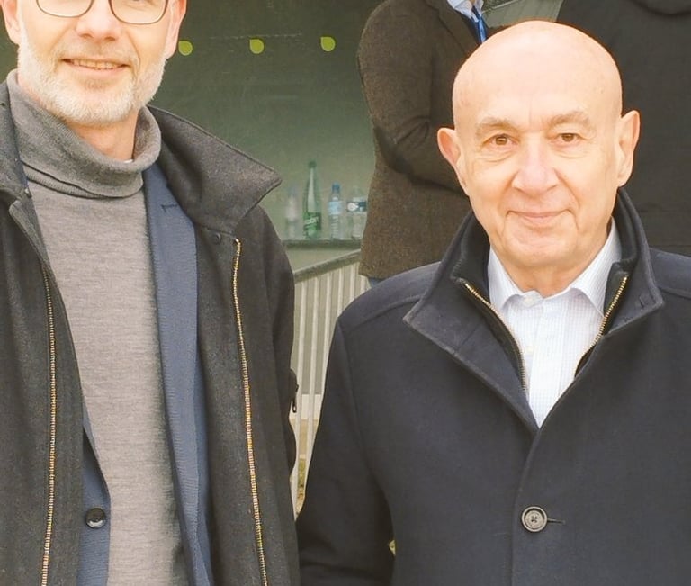 two men standing next to each other in front of a building