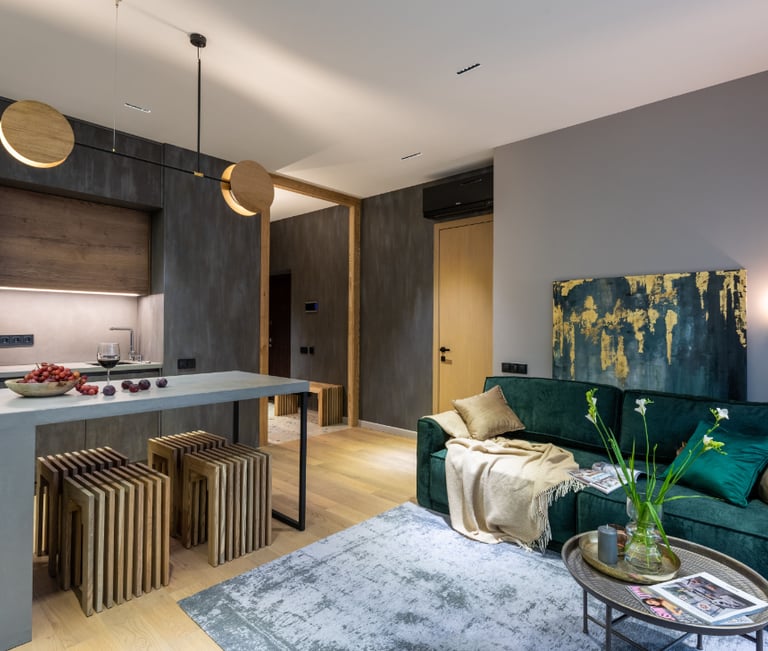 an open plan space with a emerald green sofa and coffee table and a kitchen island
