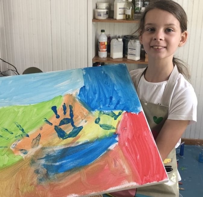 Photo de Magali STrassel, art-thérapeute, montrant une petite fille fière de montrer sa peinture