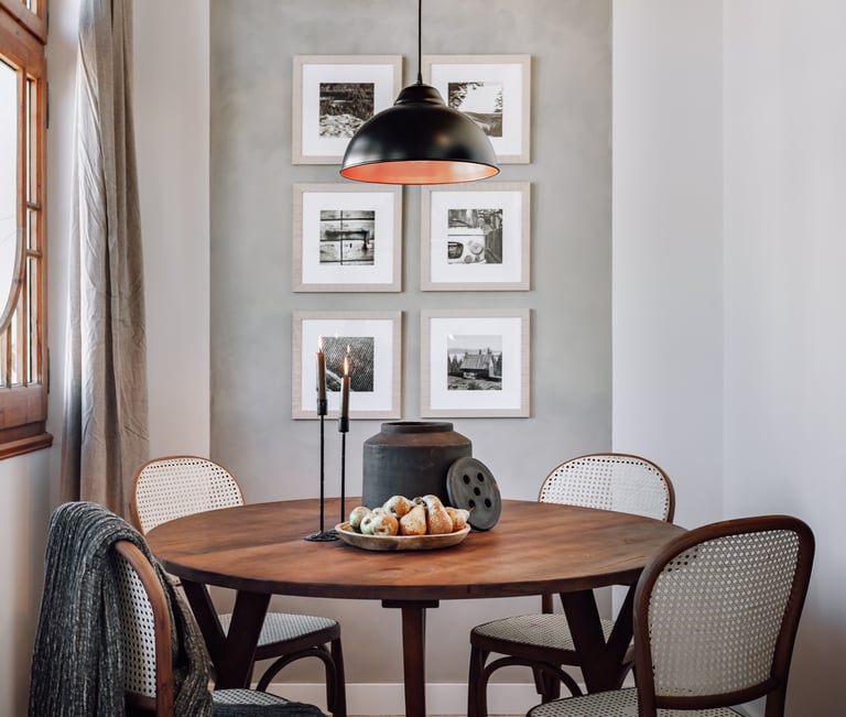 Elegant dining area with rattan and wood chairs and rustic decor elements by SAVIA interior design
