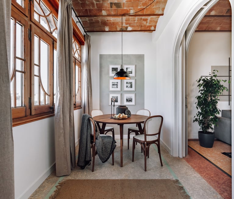 Elegant dining area with rattan and wood chairs and rustic decor elements by SAVIA interior design