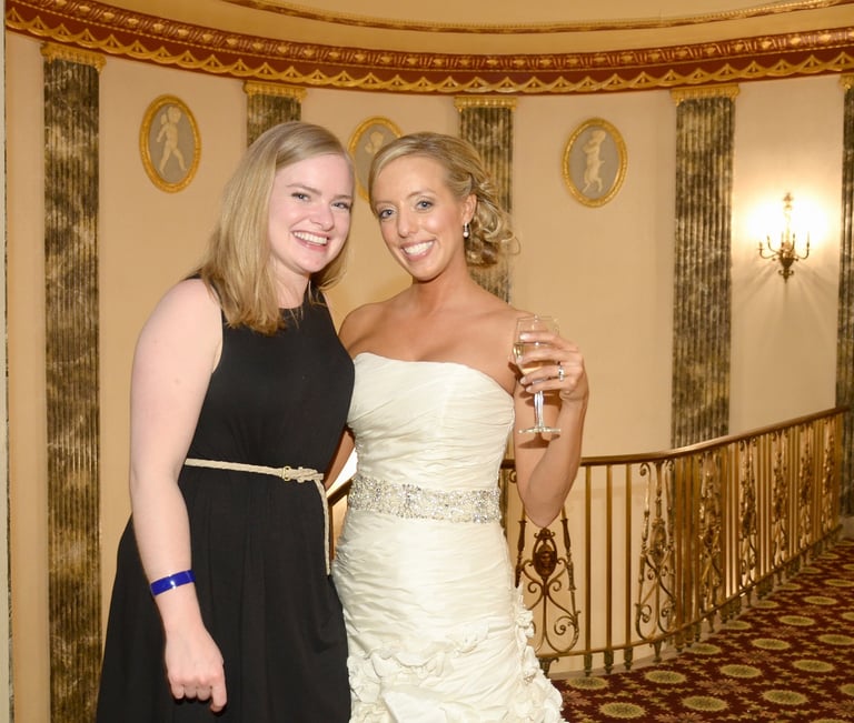 a bride and a female guest in formal wear standing in a hotel lobby