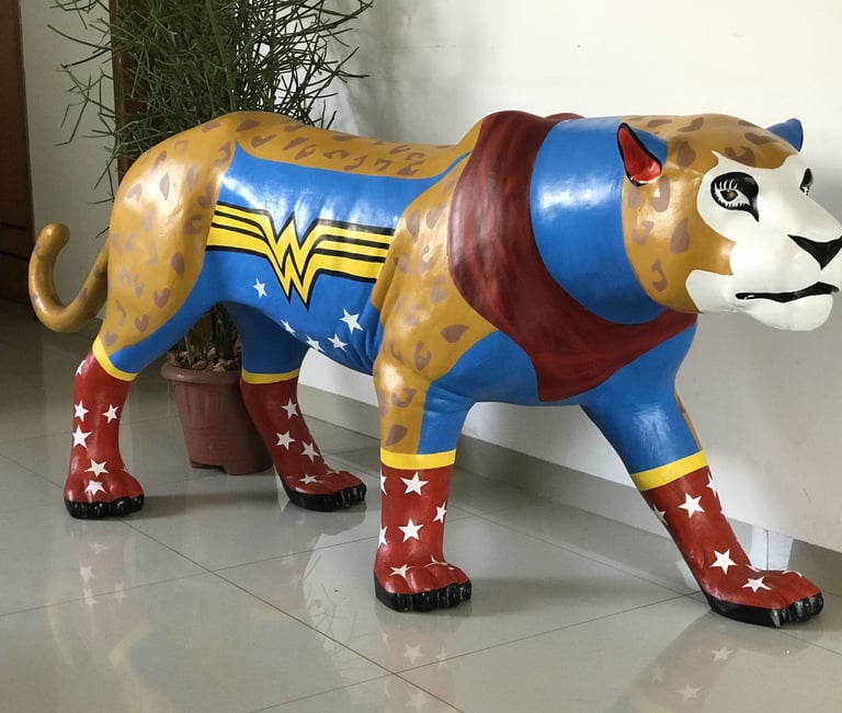 Detalhe da pintura da Onça Maravilha com padrões e cores vibrantes, alusões à Mulher Maravilha.