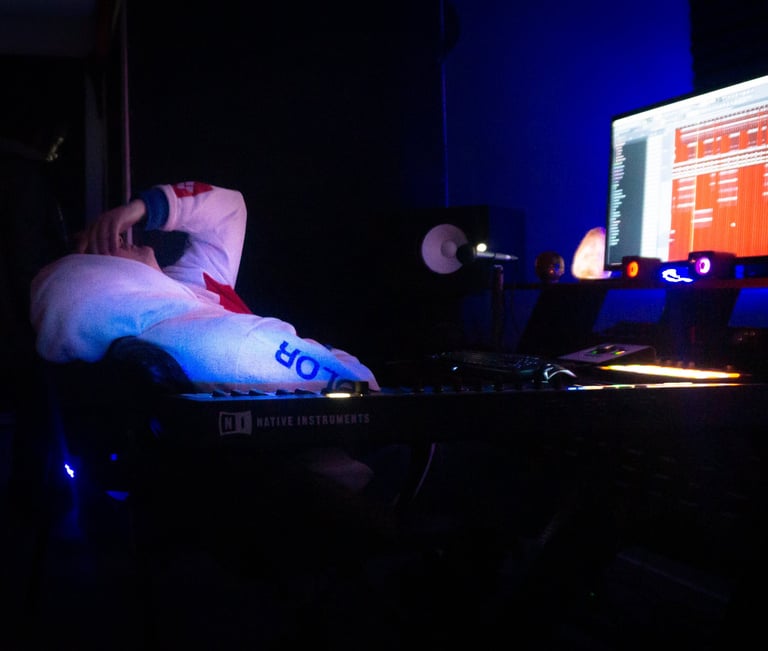 a man is slumped over in a chair in the dark. With a computer screen on.