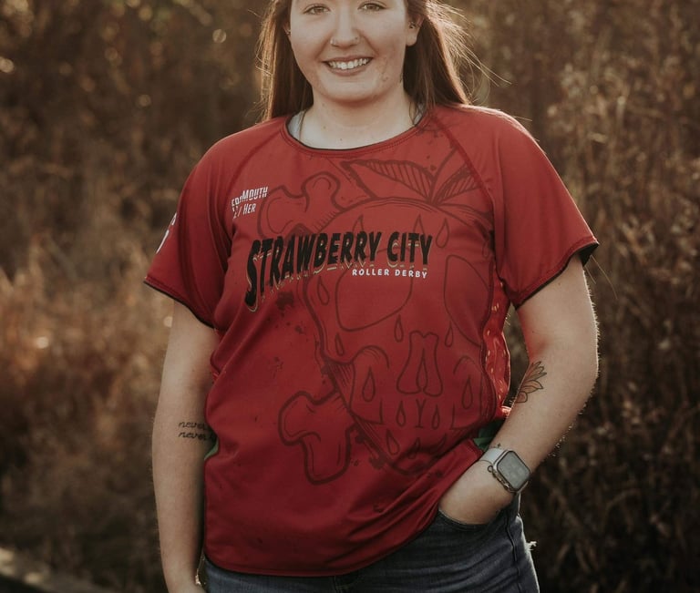 a brown haired, brown eyed woman in a red shirt and ripped jeans
