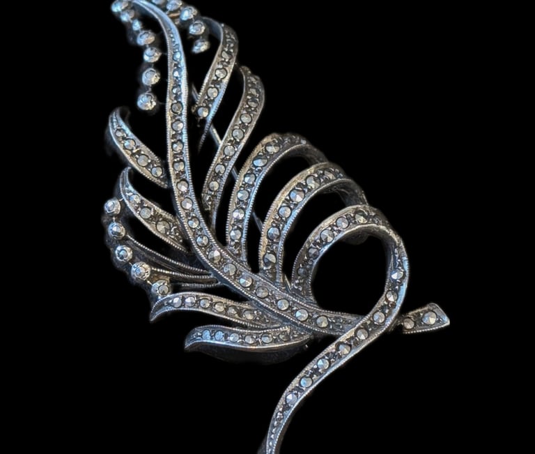 a silver and diamond feather brooch