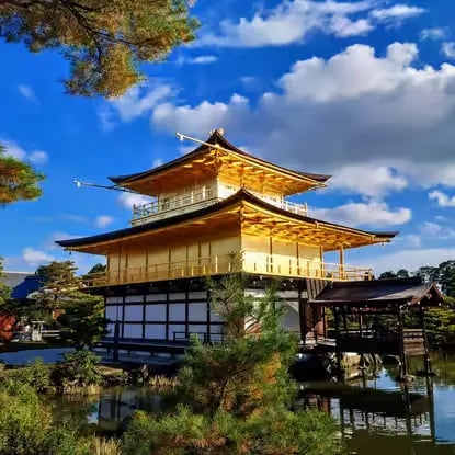 Kinkaku-ji Golden Pavilion temple reflecting in the water under a blue sky