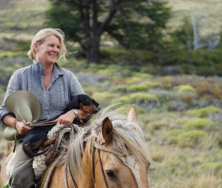 A person on horseback holding a small dog.
