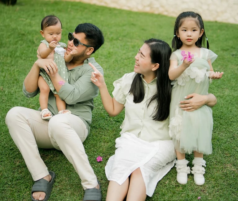 Father sitting with his children on a tropical resort lawn during a family photography session in Bali.