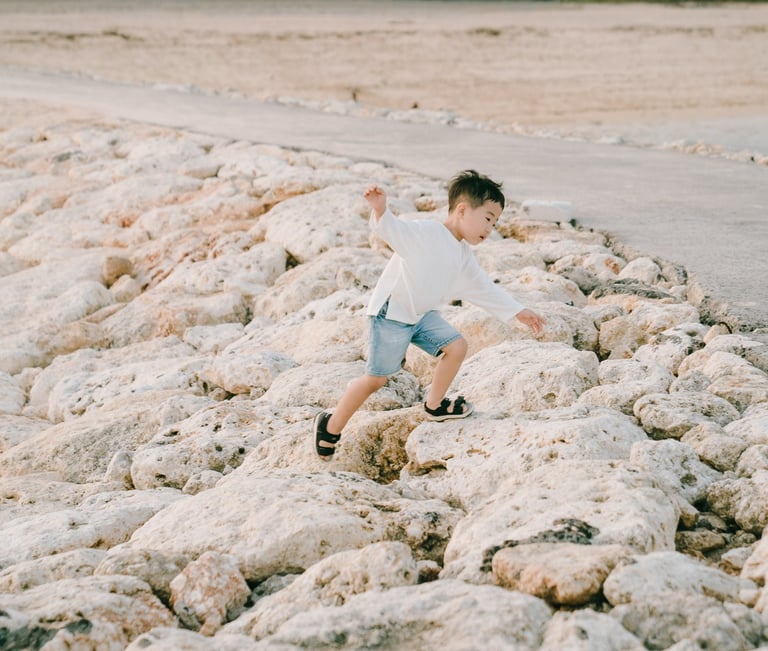 Child portrait during a family photography session at The Apurva Kempinski Bali beach rock area.