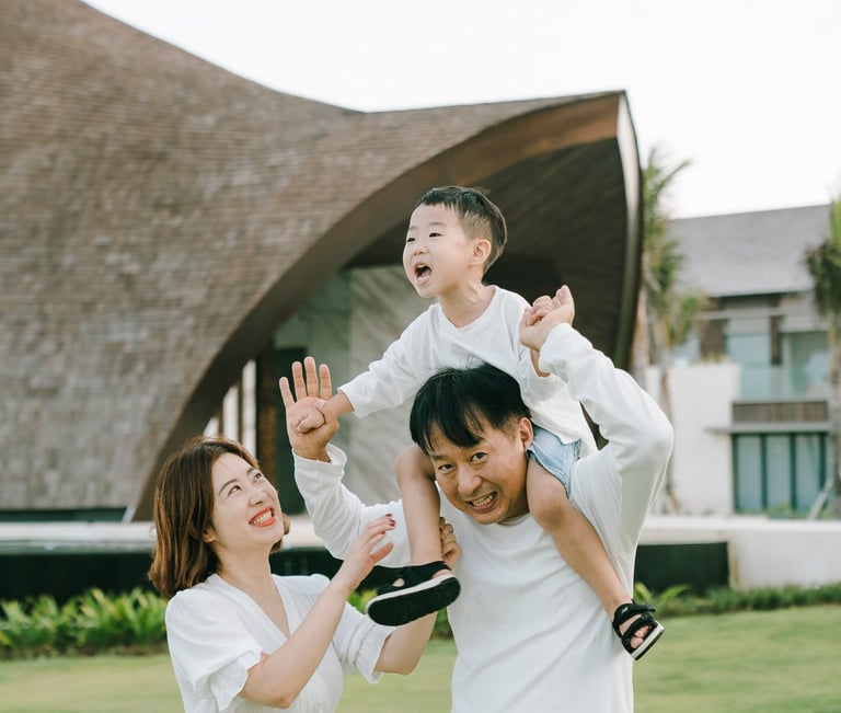 Luxury family photographer in Bali capturing a joyful father lifting his child at The Apurva Kempinski Bali.