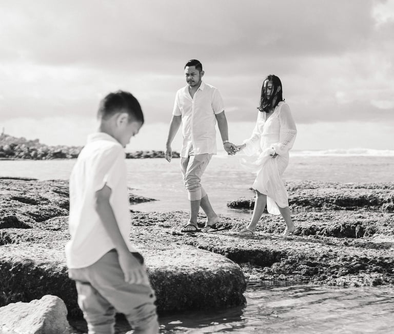 Ayunda family walking together across the rocks at Melasti Beach during sunset family photography in Bali.