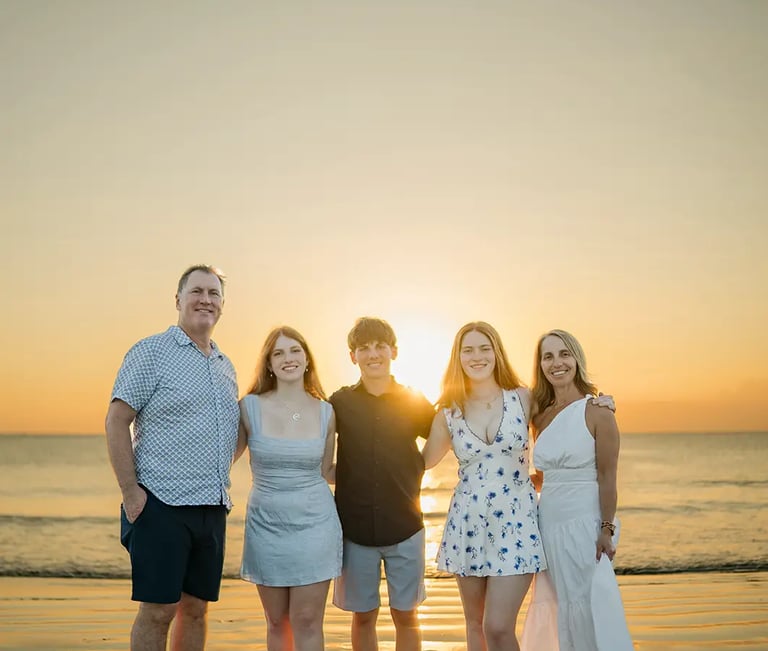 Family standing together on Jimbaran Beach during a relaxed sunset photography session in Bali