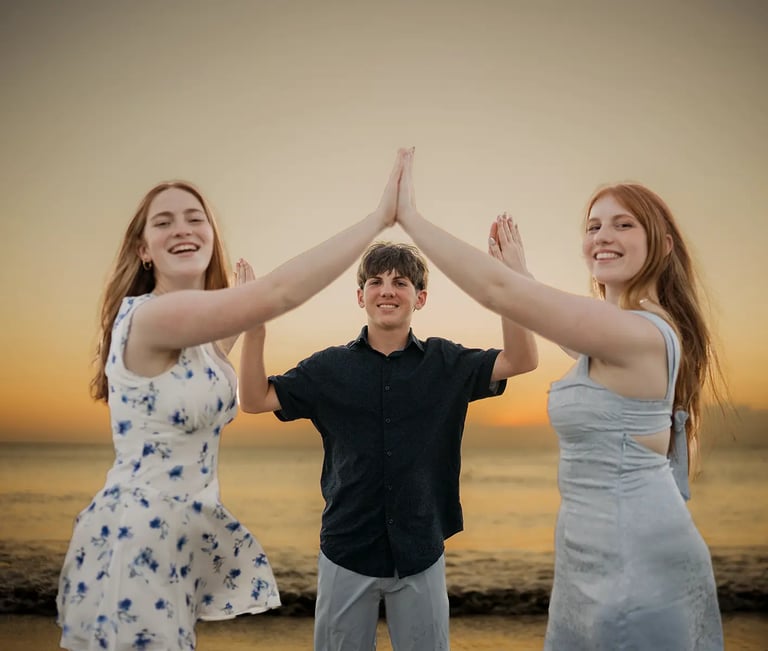 Family sharing a playful high-five during a sunset family photography session at Jimbaran Beach Bali