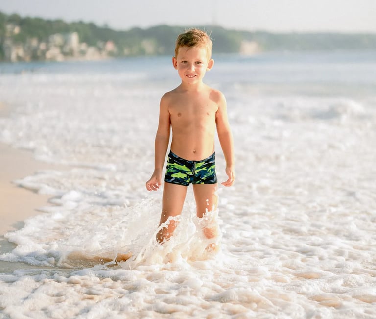 Young boy enjoying the ocean waves during a family photography session at Dreamland Beach Bali.