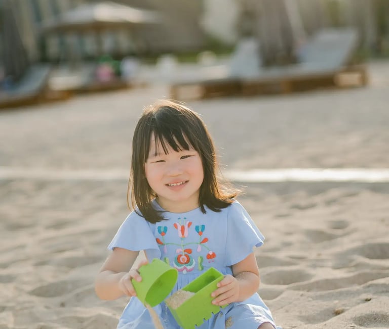 Young girl playing with sand during a family photography session at The Apurva Kempinski Bali.