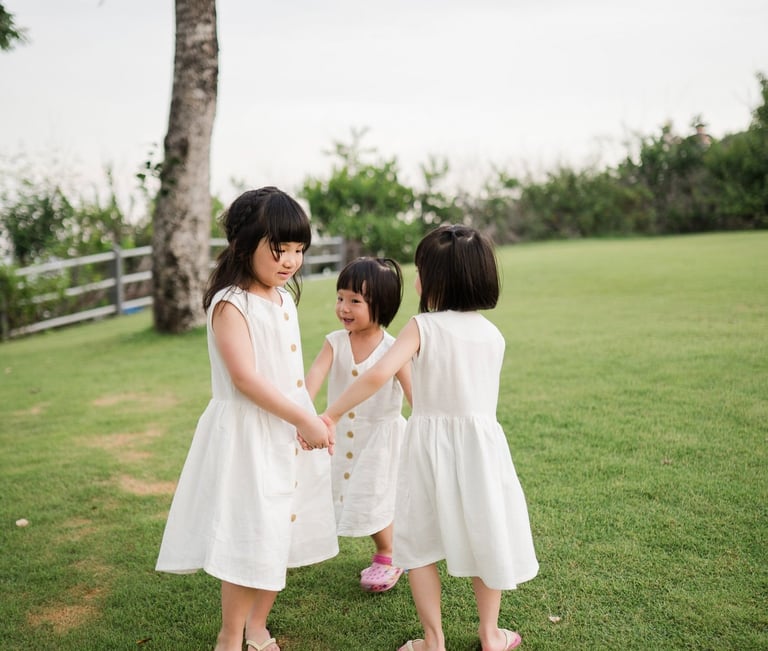 Two sisters playing together on the grass during a family photography session at The Mulia Nusa Dua Bali