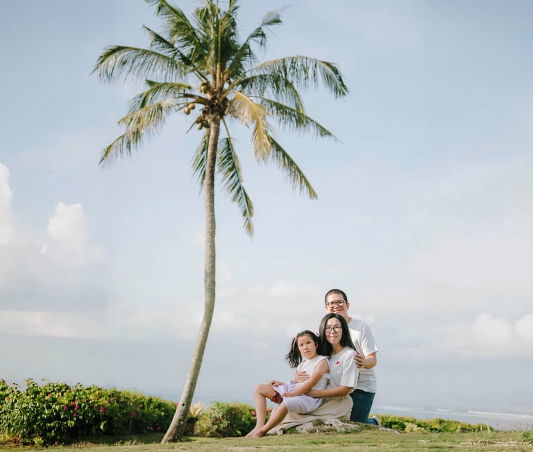 Family portrait at AYANA Villas Jimbaran Bali with ocean view and palm trees – luxury family photography in Bali