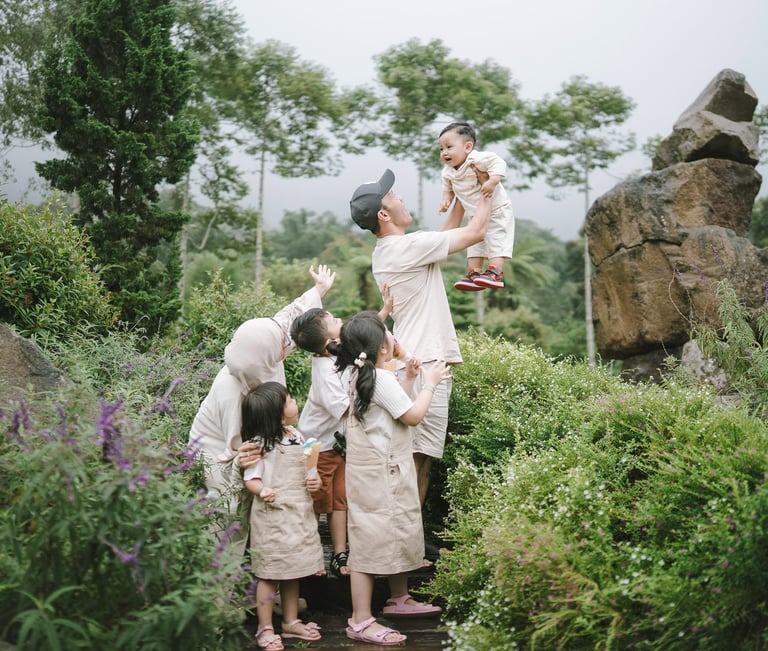Father lifting child in flower garden during a family photography session at Bali Farm House Bedugul Bali.