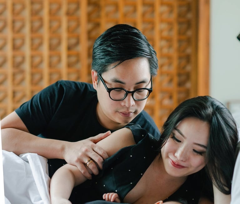 Father and mother with baby on bed during a family photography session at a private villa in Ubud Bali.