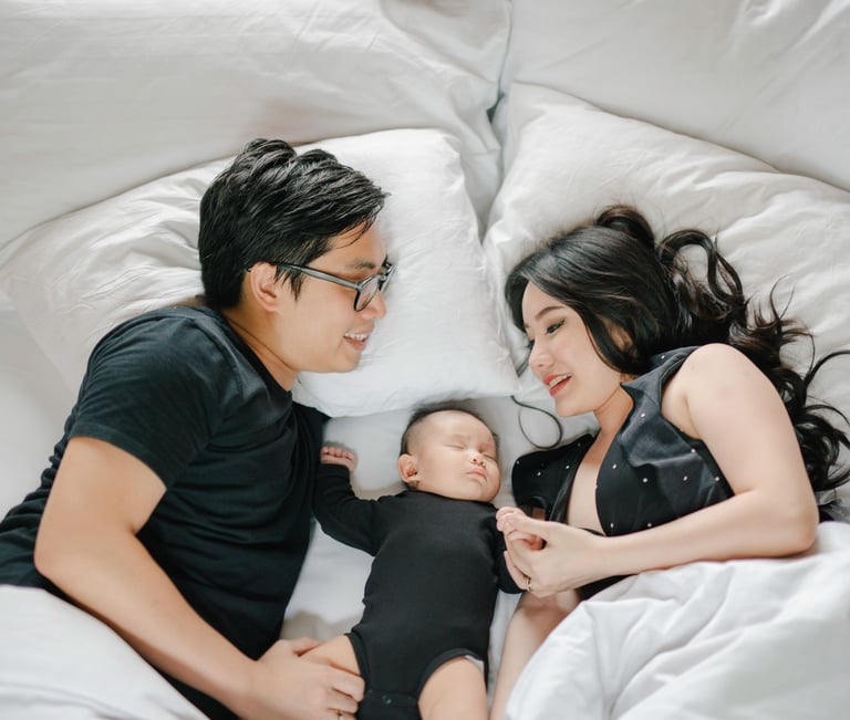 Family lying on bed with baby during a family photography session at a private villa in Ubud Bali.