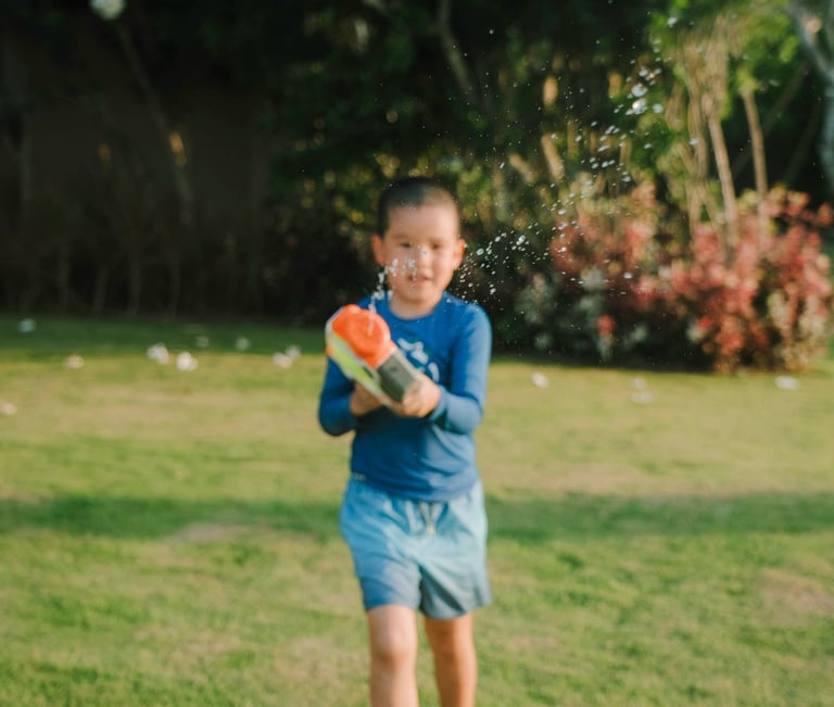Children playing with water guns during a family photography session at AYANA Villas Jimbaran Bali