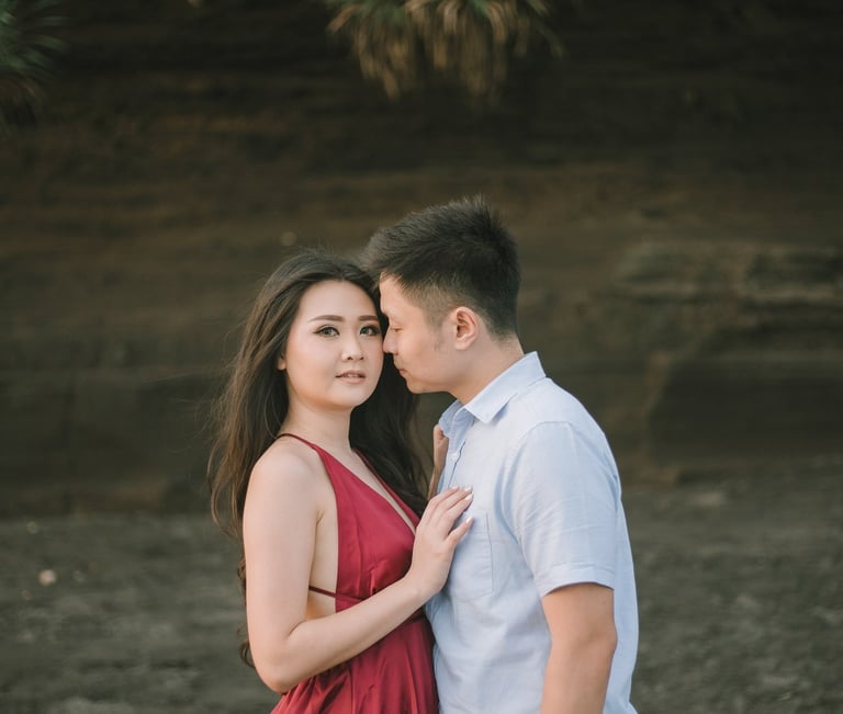 Romantic couple portrait under the cliff at Pantai Nyanyi Bali during sunset.