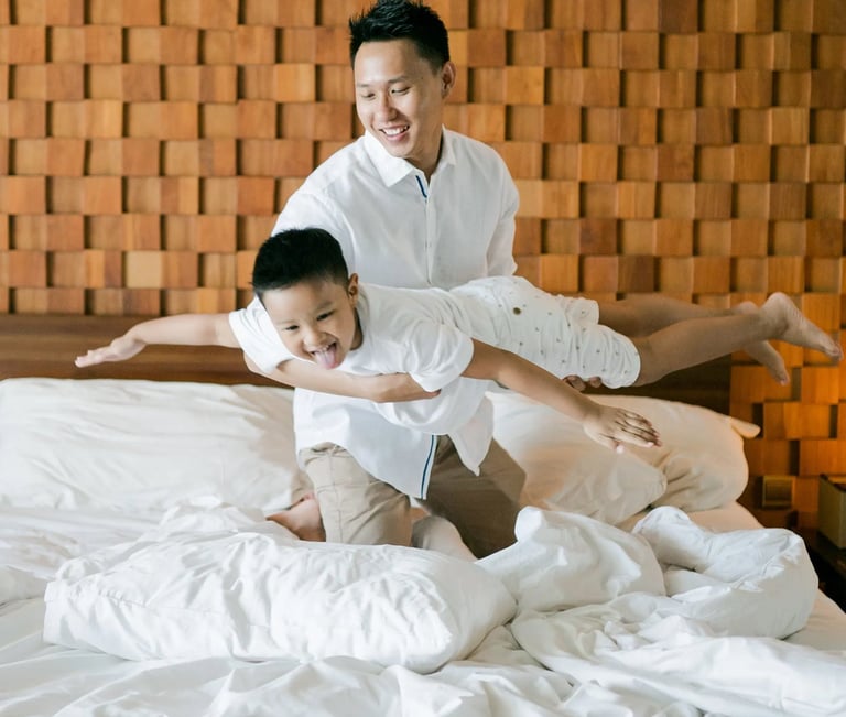 Playful family moment on the bed during a relaxed indoor family photography session at Anantara Uluwatu.