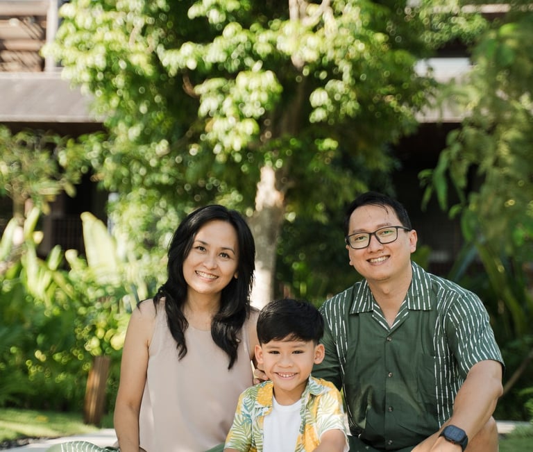 Family sitting together on garden pathway during a relaxed family photography session at The Meru Sanur Bali