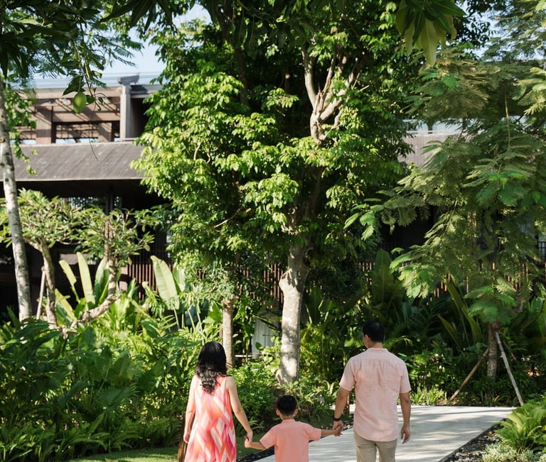 Parents holding their child while walking through tropical garden at The Meru Sanur Bali family photography