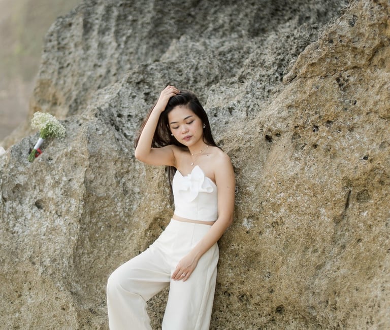 Bride portrait standing by coastal cliff during sunset photoshoot at Melasti Beach Bali