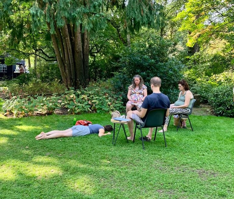 a group of people sitting in chairs in a grassy area