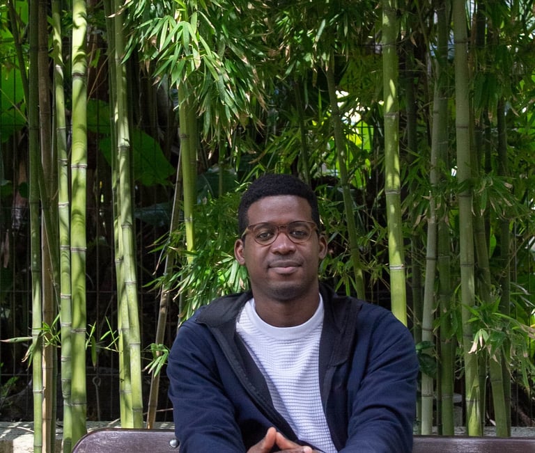 man  with glasses sitting in front of bamboo 