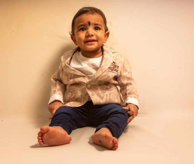 a baby sitting on a white surface with a white background